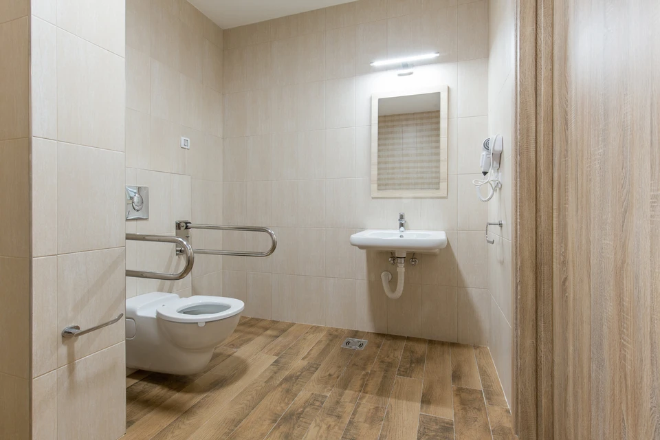 Plombier professionnel en casque blanc et lunettes de protection installe une colonne de douche thermostatique dans salle de bain carrelée
